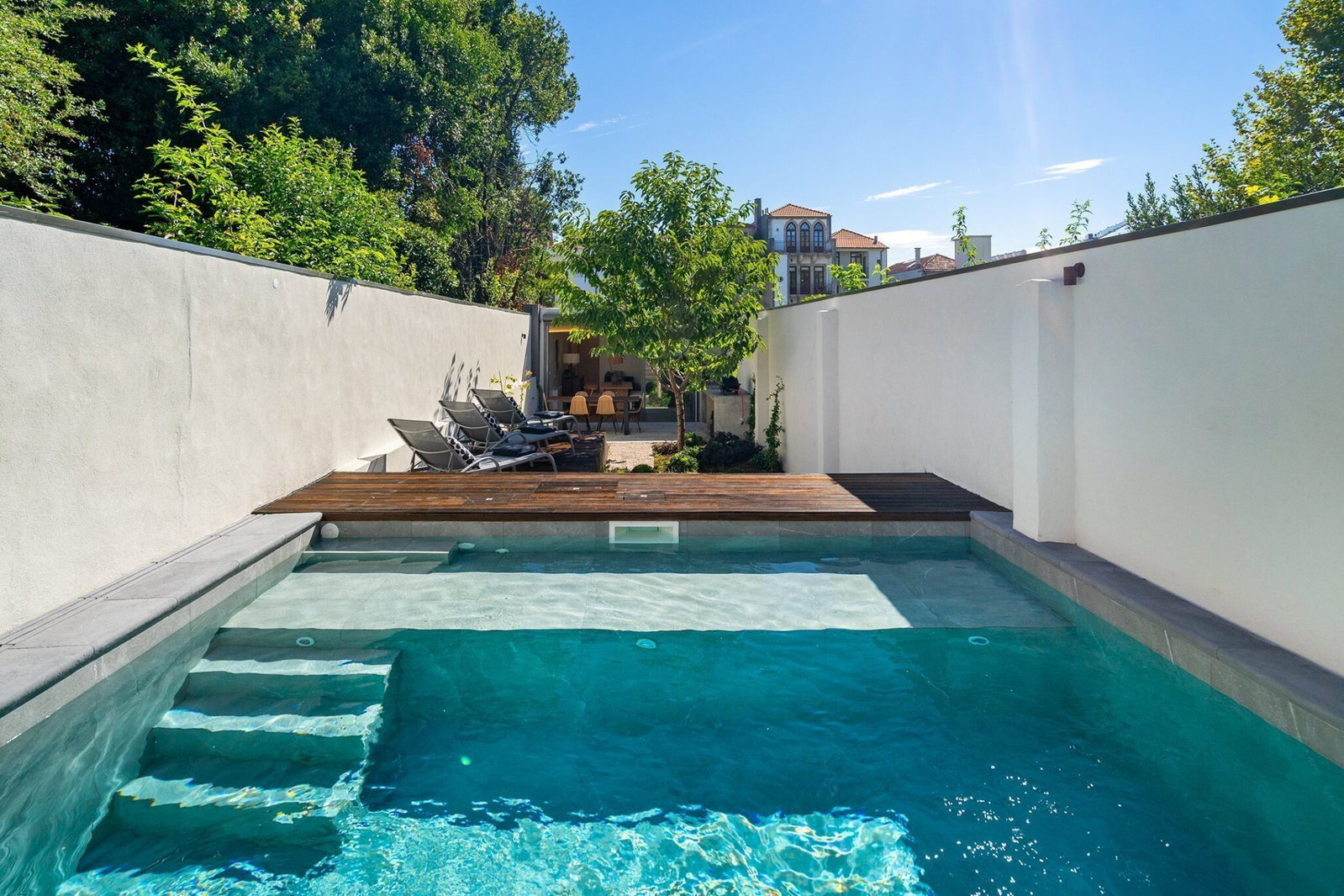 La piscina privada de Villa Almada con su solárium, tumbonas y la villa al fondo en Oporto