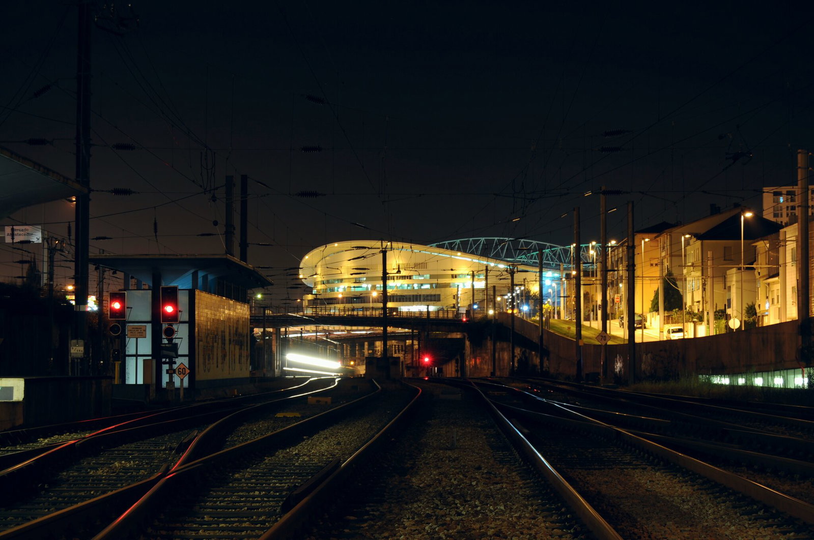 Rail and metro lines approaching Est&aacute;dio do Drag&atilde;o at night with the stadium lit