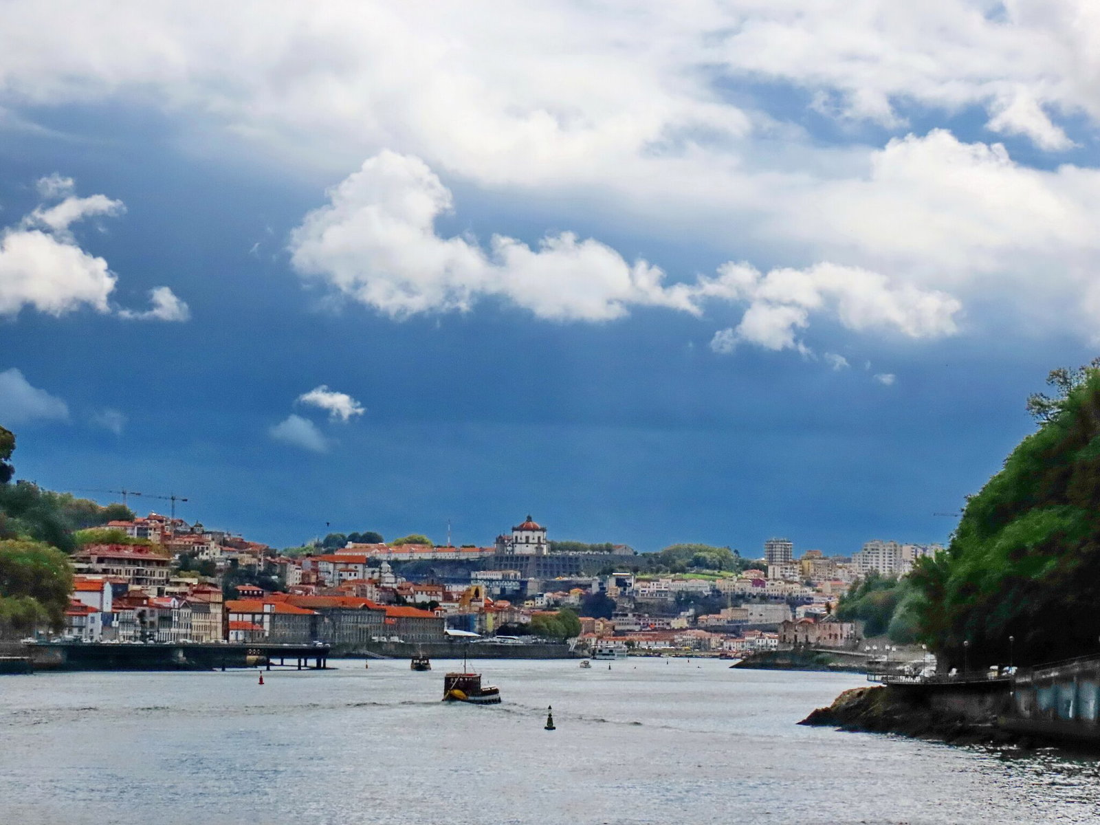 Storm clouds gathering over the Douro river and Porto waterfront with a rabelo boat