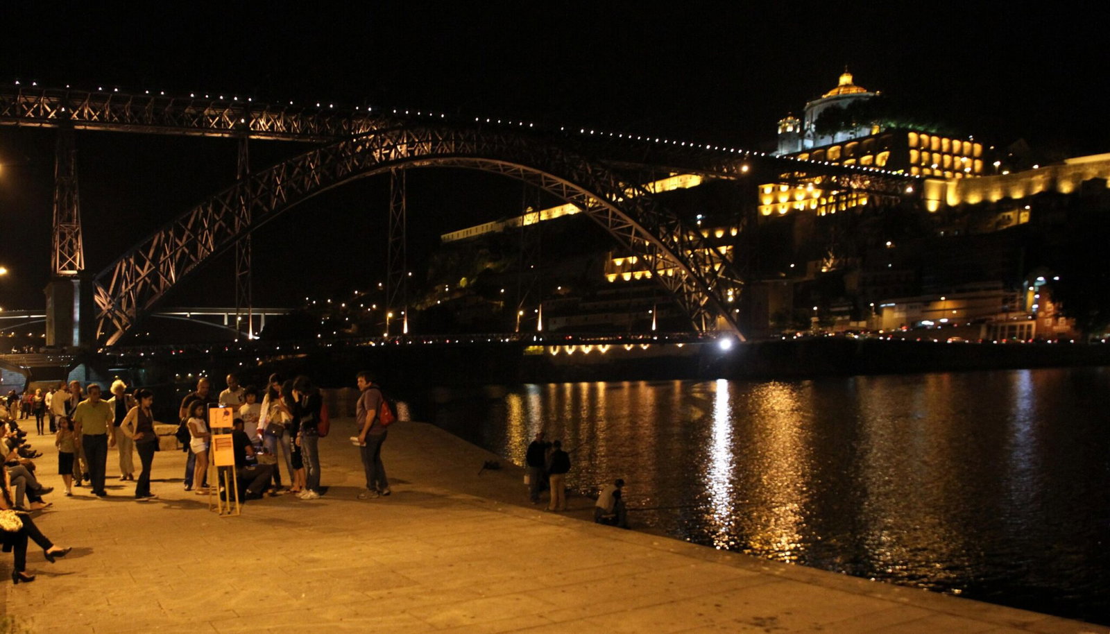 El puente Dom Luis I y el monasterio de Serra do Pilar iluminados por la noche, vistos desde Cais da Ribeira en Oporto