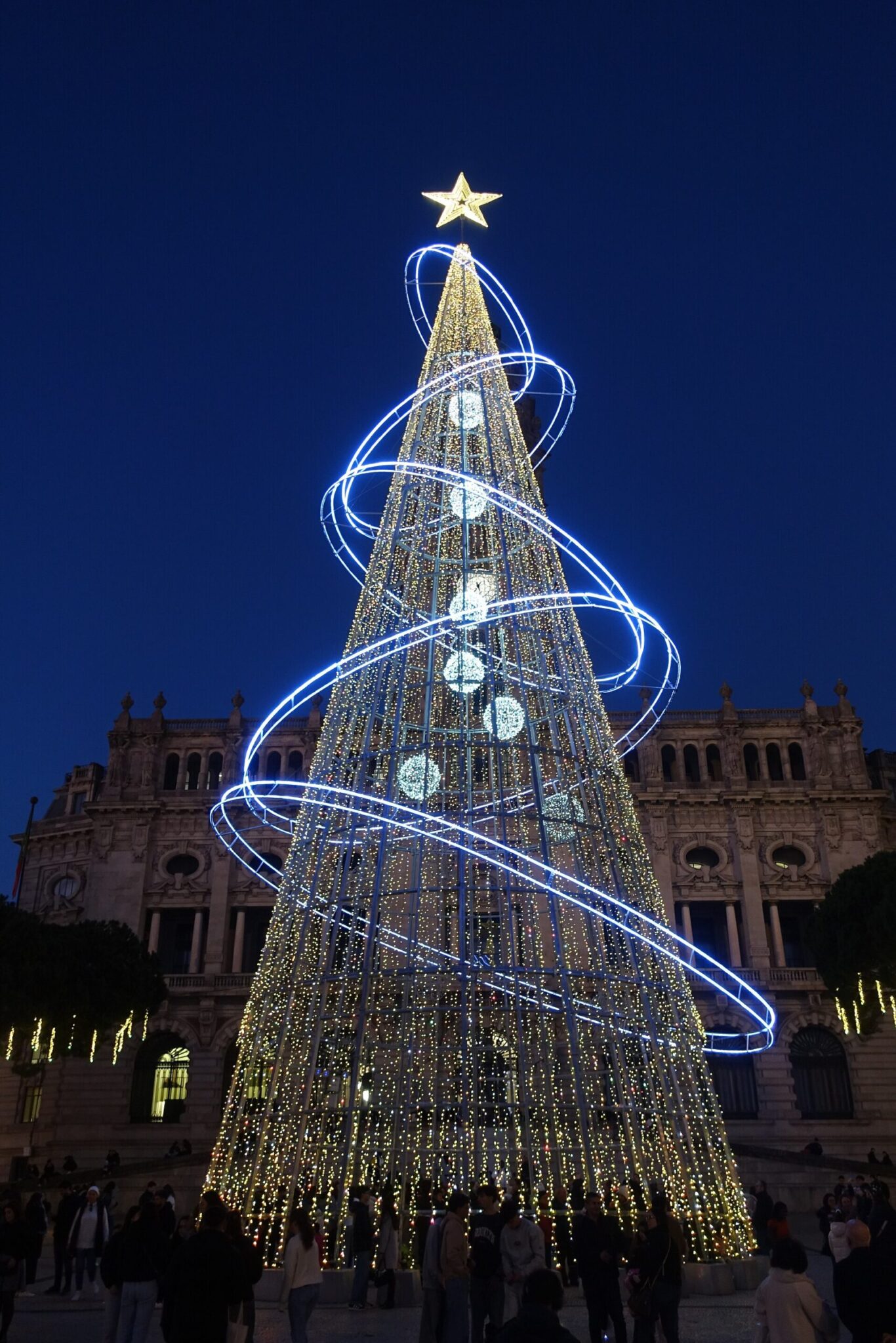 El árbol de Navidad iluminado con luces azules en espiral frente al Ayuntamiento de Oporto al anochecer
