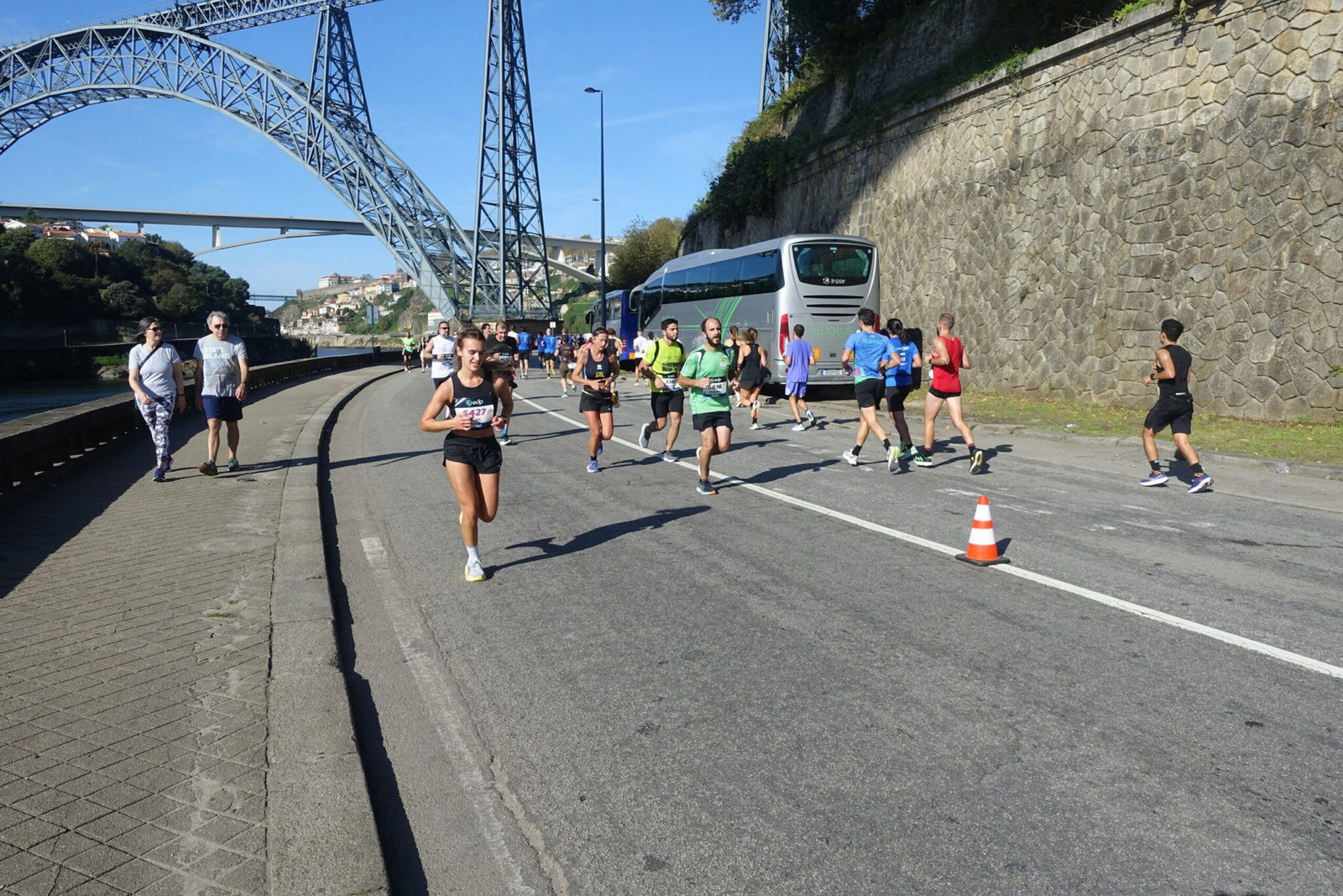 Porto Marathon runners passing beneath the Maria Pia bridge on the Douro riverside road