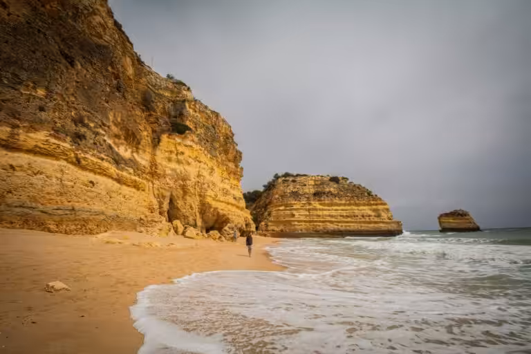 The golden cliffs and sea stacks of Praia da Marinha in the Algarve under a grey autumn sky