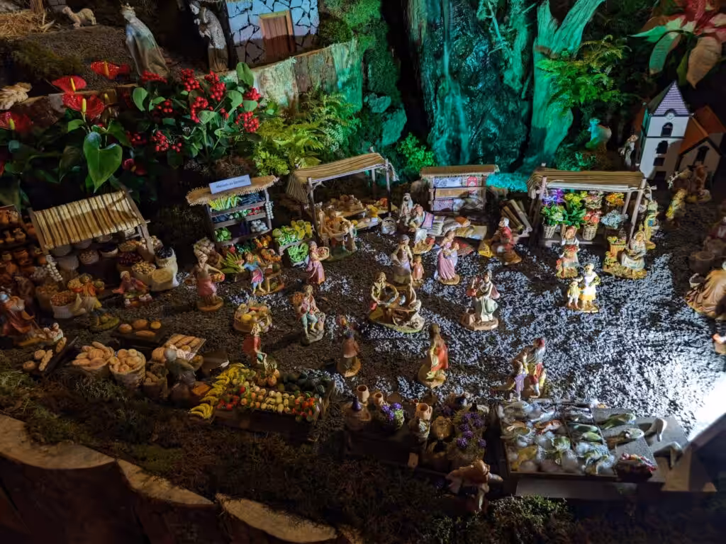 A church nativity scene in Madeira with figures, market stalls and a lit waterfall